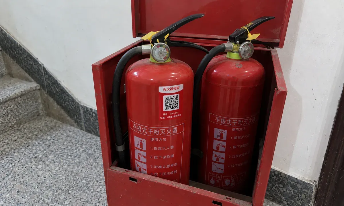 灭火器箱里两具手提式干粉灭火器，左边瓶体上贴着灭火器检查二维码标签