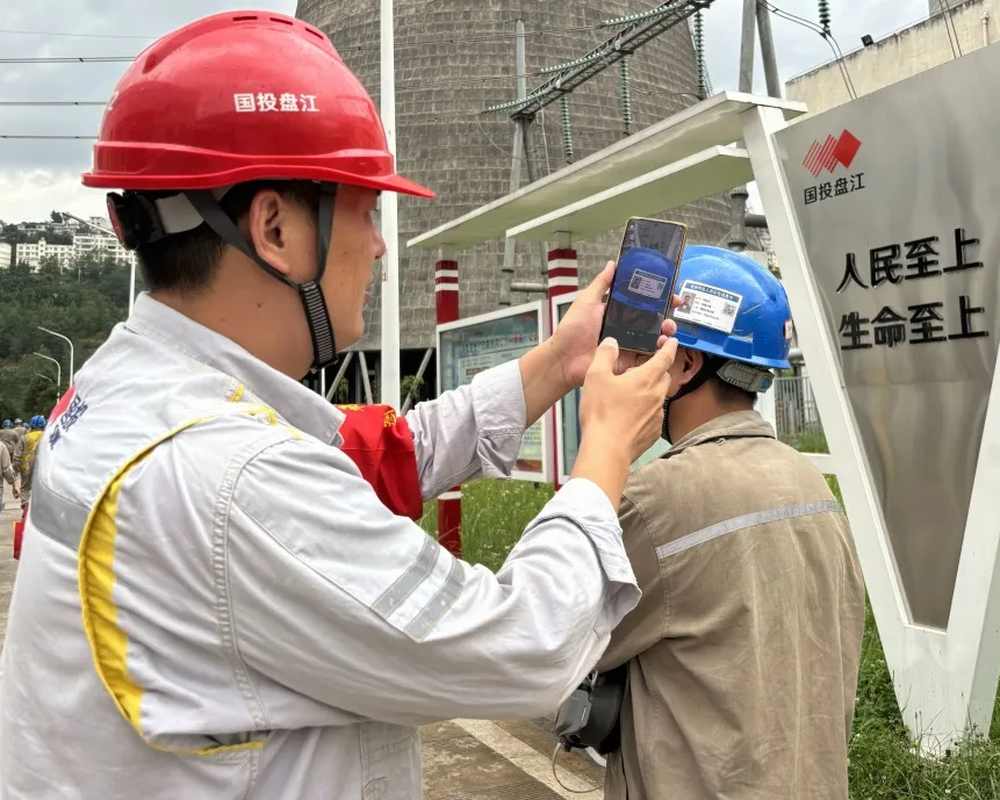 国投盘江检修现场，管理人员用手机扫描作业人员安全帽上的实名信息卡二维码
